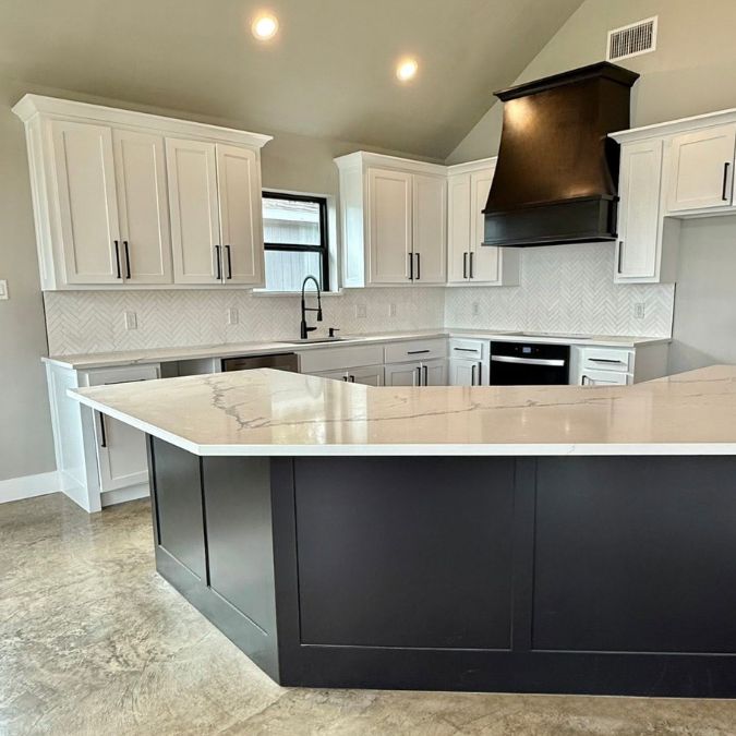 Custom home interior built by custom home builders in Athens TX showing modern kitchen with black island, white shaker cabinets, and polished concrete floors.