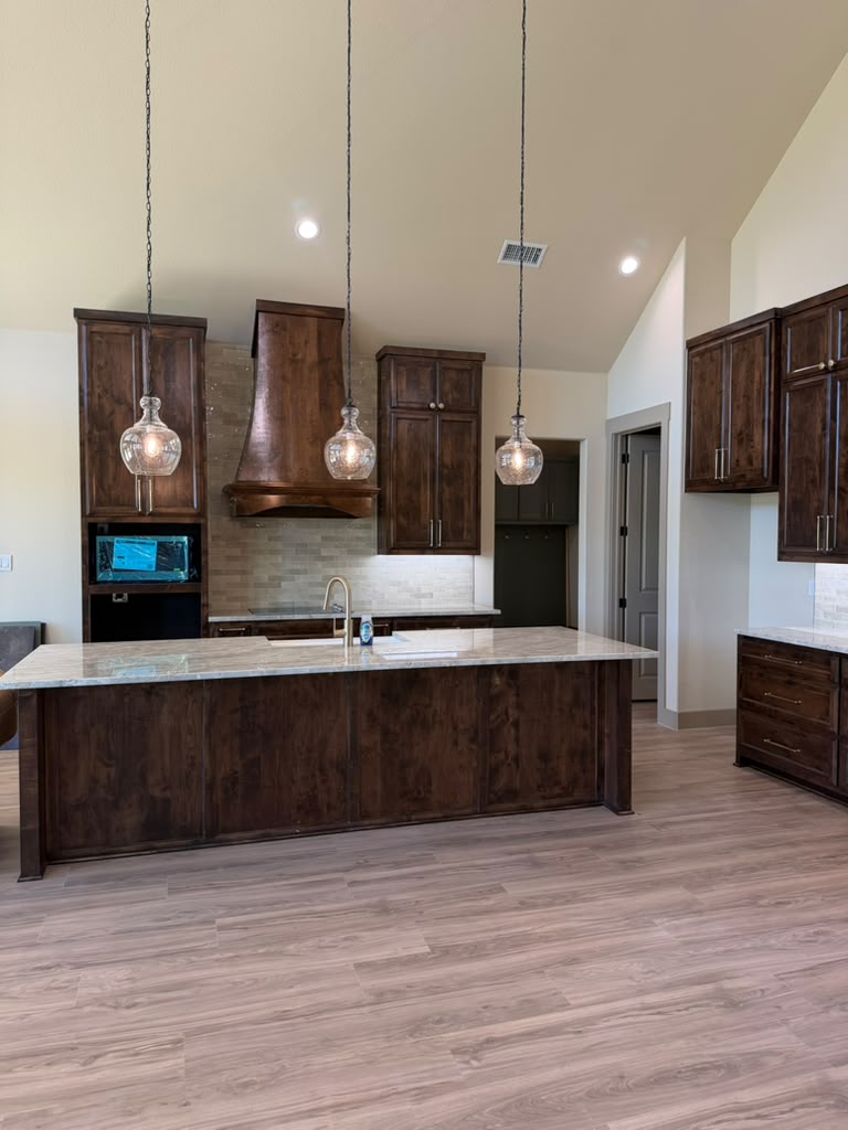 Custom kitchen renovation featuring dark wood cabinets and a granite island built by custom home builders in Canton TX.